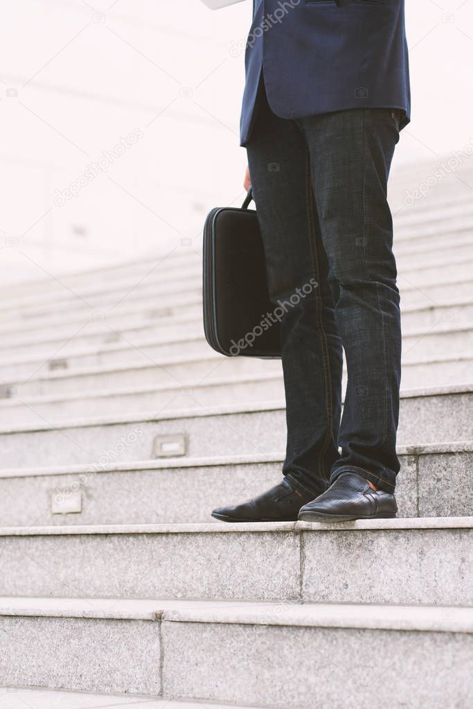 Cropped image of businessman with briefcase standing on steps
