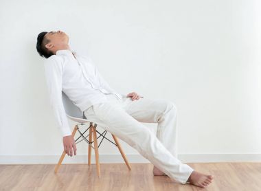 Sandalyede uyuyor basit Beyaz giysili genç Asyalı adam