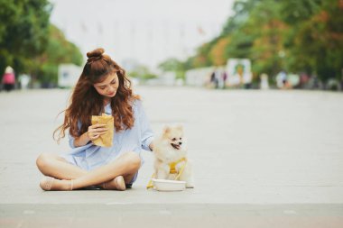 Genç ve güzel kadın ve köpeğini açık havada oturma ve aperatifler sahip