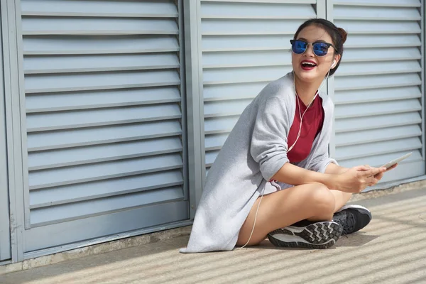 スマート フォンで外に座っている陽気な若いアジア女性 — ストック写真