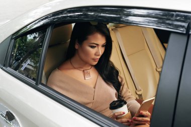 Güzel genç kadın arabada oturup, kahve içme ve kısa mesaj okuma