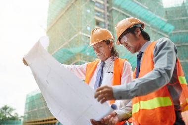 Vietnamca inşaat işçileri dikkatle inceleyerek yapı planı