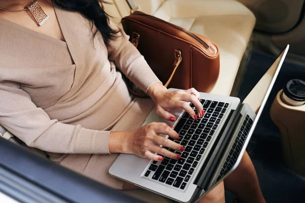 Business lady working on laptop when using taxi to go to work