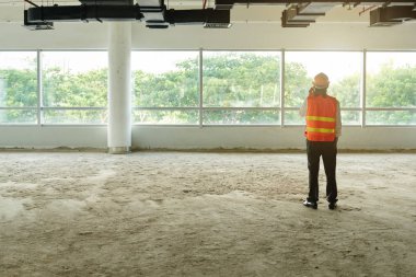 Ayakta boş bitmemiş kat mühendis ve telefonla arayan, arka görünüm