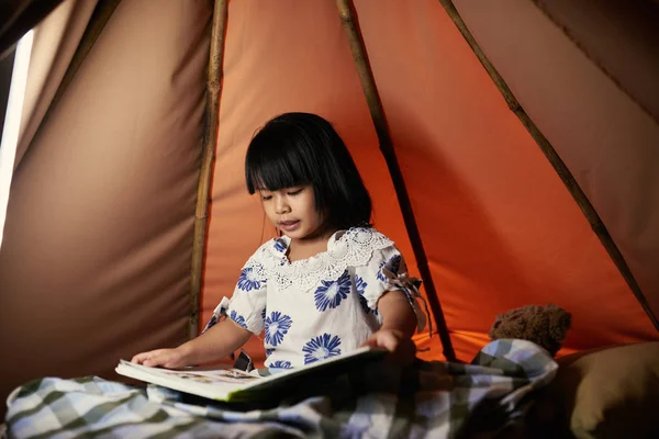 素敵なのベトナムの少女がテントの中で座っているときに読んで — ストック写真