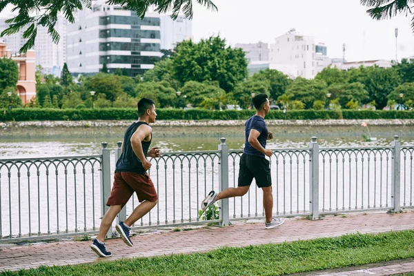 Friends jogging along the river in the morning