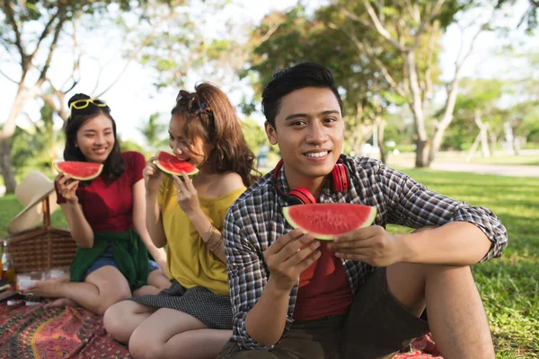 Vietnamese young people enjoying fresh watermelon at picnic in the park