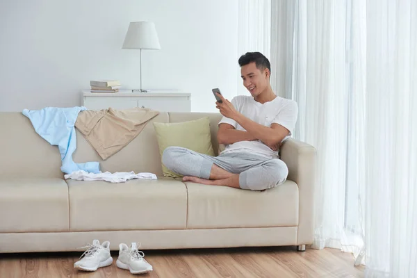 Hombre Alegre Sentado Sofá Con Teléfono Inteligente Ropa Sucia Por — Foto de Stock