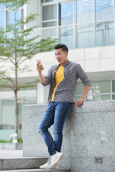 Opgewonden Jonge Aziatische Man Nieuws Smartphone Scherm Lezen — Stockfoto