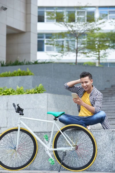 Joven Sentado Cerca Bicicleta Leyendo Noticias Teléfono Inteligente — Foto de Stock
