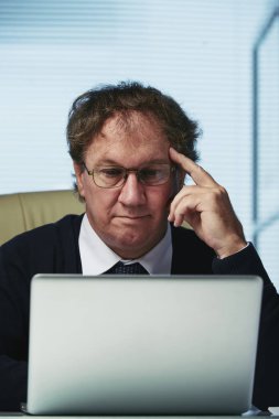 Dizüstü ekran üzerinde makale okuma bardaklarda dalgın girişimci portresi