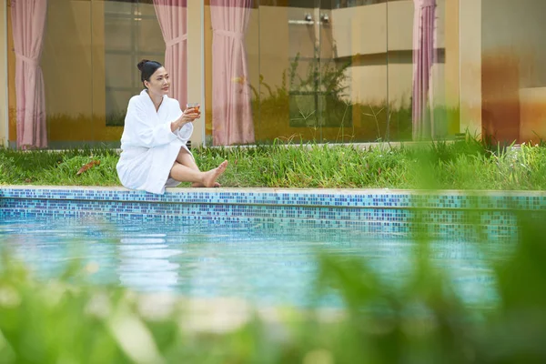 デトックスのお茶を飲みながら物思いにふけるアジアの若い女性とプールで休憩 — ストック写真