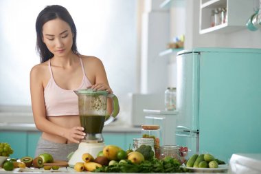 Yeşil smoothie yapmak blender kullanarak güzel Asyalı kadın