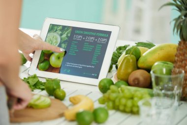 Yakın çekim görüntü kadın yeşil smoothie formülü tablet ekranında okuma
