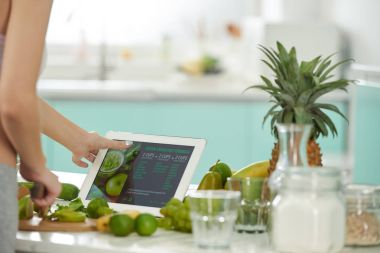 Dijital tablet üzerinde yeşil smoothie formülünü izlemek kadın