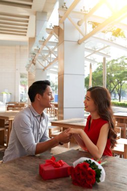 Elele ve kafede masada konuşurken sevgi dolu genç Çift