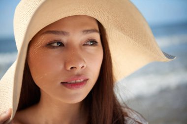 Sahilde hasır şapka giyen oldukça Asya genç kadın yüzü