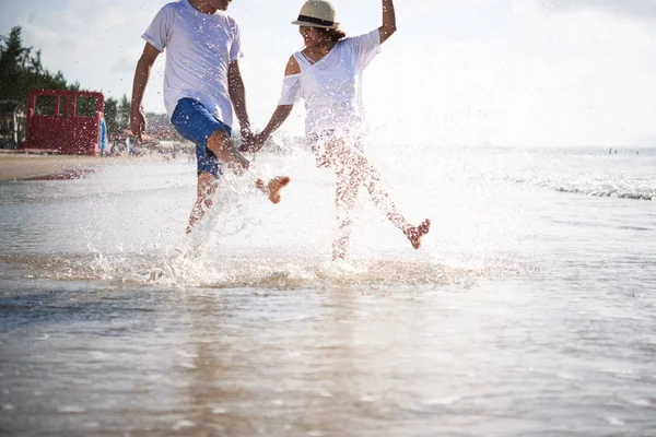 快乐的年轻夫妇在海滩漫步时溅水 — 图库照片