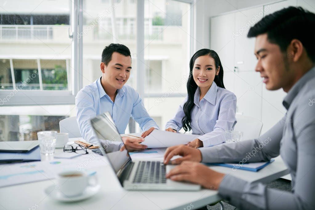 Smiling asian business lady having meeting with coworkers