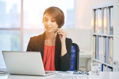 Güzel iş kadını istemciye çağrılırken kulaklık kullanarak