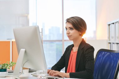 Ofiste bilgisayar üzerinde çalışan çekici kadın