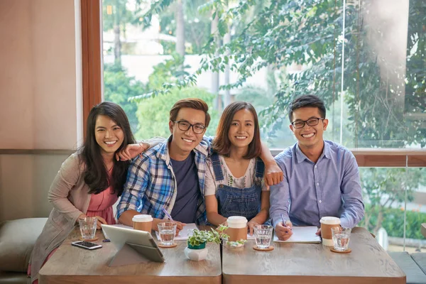 一群快乐的越南朋友坐在咖啡馆里喝咖啡和课本 — 图库照片