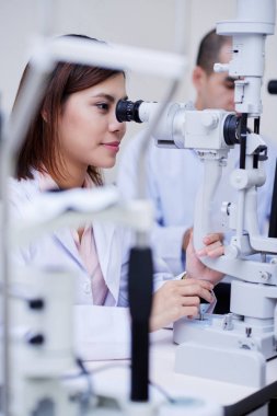 Mikroskop kullanarak genç Vietnamlı kadın laboratuvar işçi