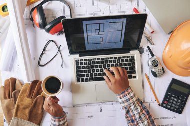 Kahve içme ve planı ile dizüstü bilgisayar ekranında çalışan mimar