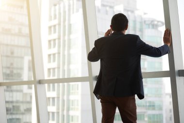 Telefonla arama ve pencereden izlerken işadamı arkadan görünüş