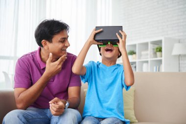 Baba ve oğul evde kanepe, sanal gerçeklik kask kullanarak çocuk