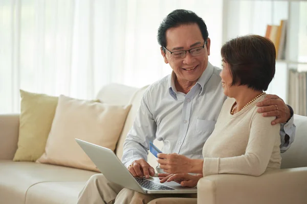 couple entering credit card information, shopping online with laptop