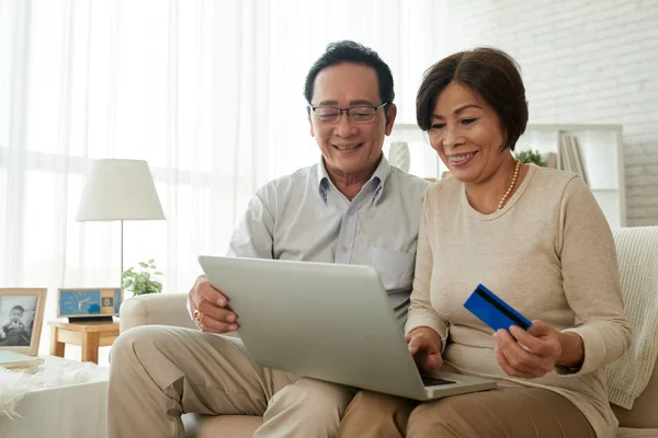 快乐高级越南夫妇与笔记本电脑和信用卡购物在线 — 图库照片