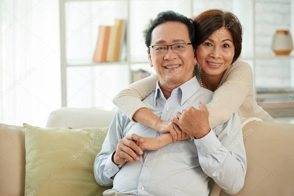 Portrait of happy aged Vietnamese couple smiling and looking at camera