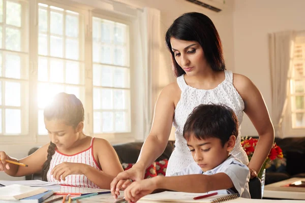 母亲检查她的儿子和女儿做家庭作业 — 图库照片