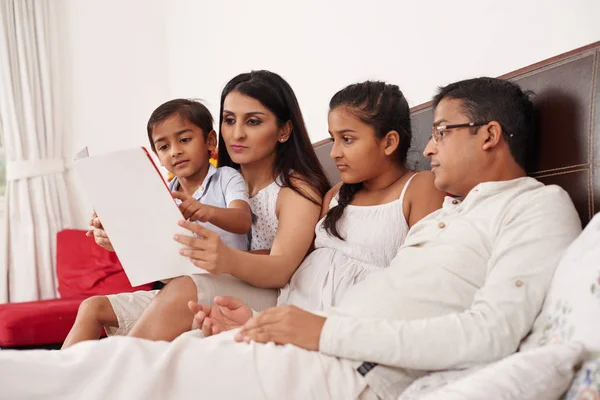 印度家庭躺在床上一起读一本书 — 图库照片