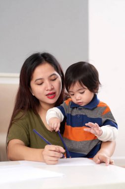Oğlunu nasıl çizileceğini gösterilen genç Filipino kadın
