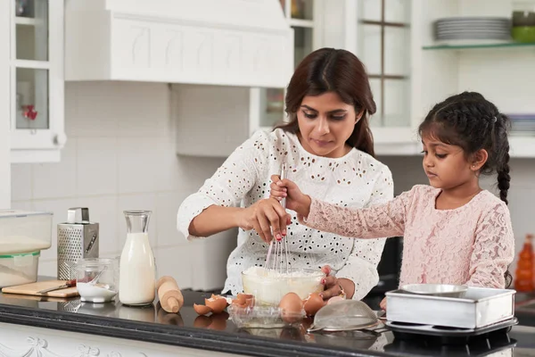 印度女人和可爱的小女儿打鸡蛋和面粉与搅拌 而在厨房做美味的馅饼 — 图库照片