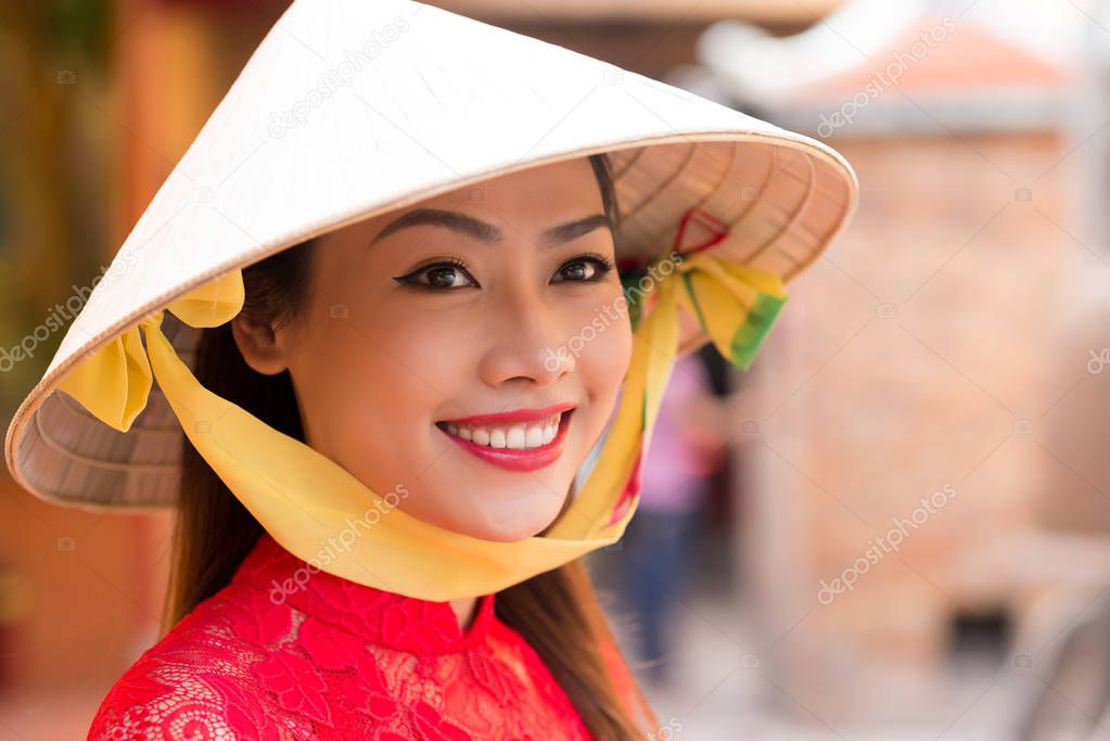 Head and shoulders portrait of attractive Vietnamese woman wearing conical hat 