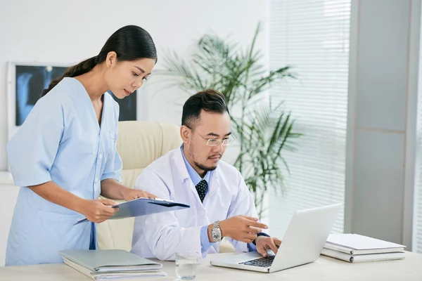 亚洲医生和护士讨论笔记本电脑屏幕信息 — 图库照片