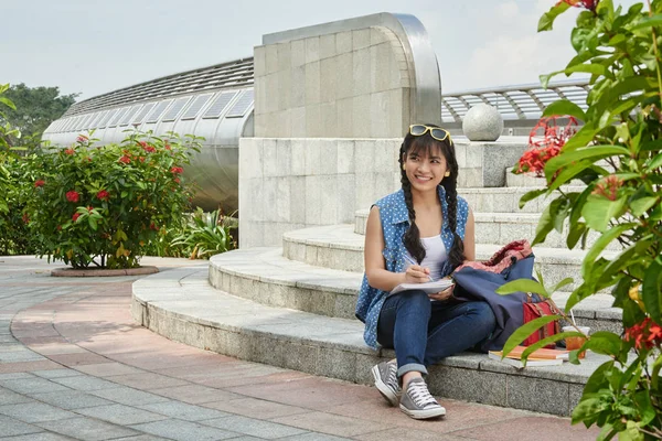 在大学校园里坐在楼梯上的快乐亚裔学生的全长作业 — 图库照片