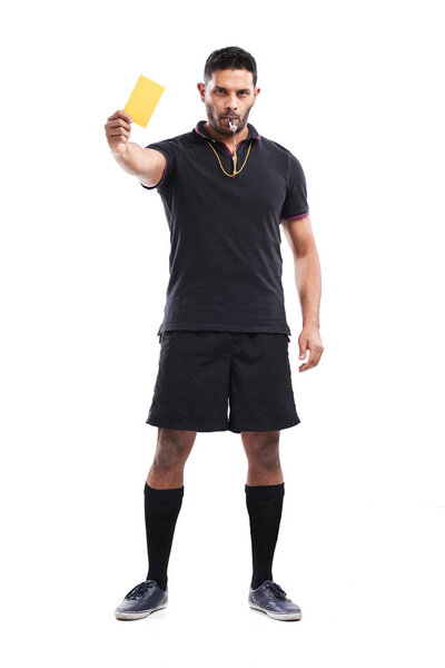 mixed race soccer referee showing yellow card and blowing whistle while standing against white background