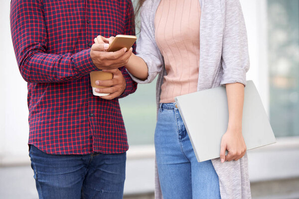 Cropped image of coworkers reading message on smartphone