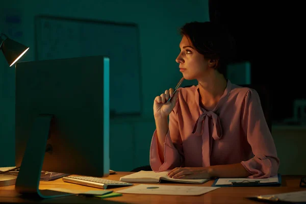 暗いオフィスで働く物思いにふけるビジネス女性 — ストック写真