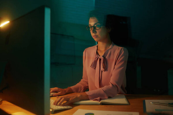 Красивая молодая предпринимательница работает в офисе до поздней ночи
