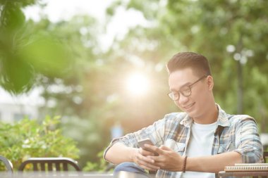 Mutlu genç adam parkta oturan güneşli gün ve manifatura arkadaş grubu