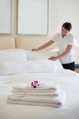 Hizmetçi havlu yığını odaklanmak için Konuklar, yatak yapma