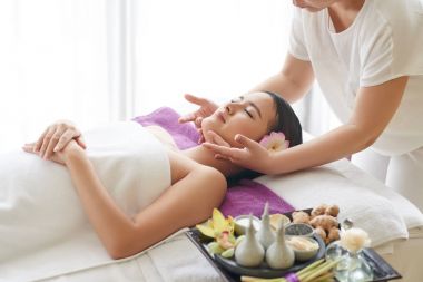 Kadının genç güzel istemci için yüz masajı yapması