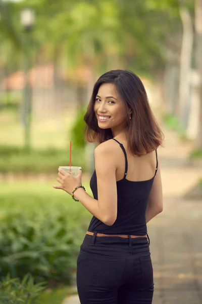 在阳光公园散步和冰茶提神的迷人年轻女子的后景色 — 图库照片