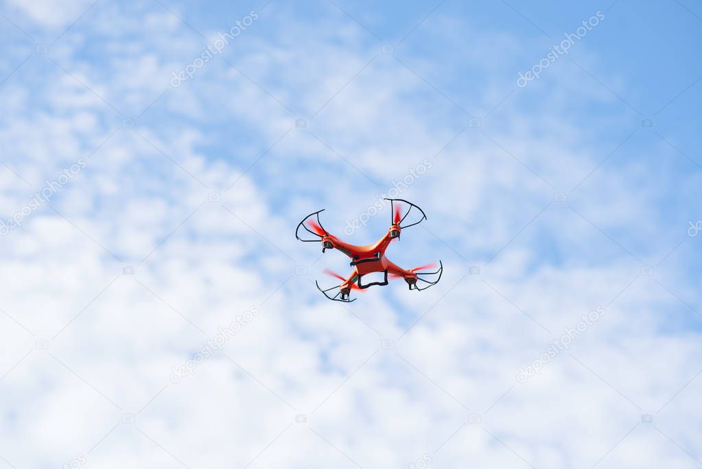Orange drone flying in blue sky