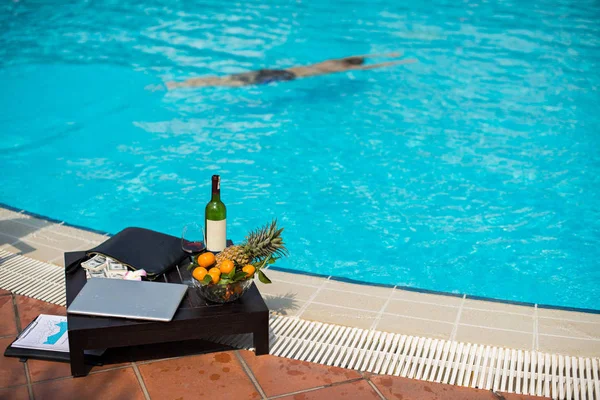 Tavolo Con Soldi Frutta Laptop Sul Tavolo Accanto Alla Piscina — Foto Stock